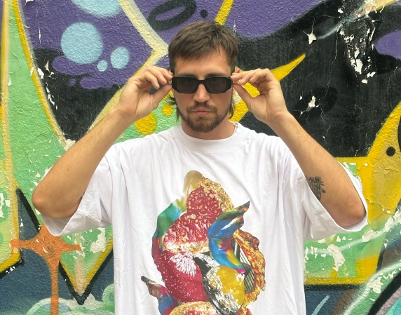 Portrait of Guido Coccia in sunglasses in front of a colorful painted wall.